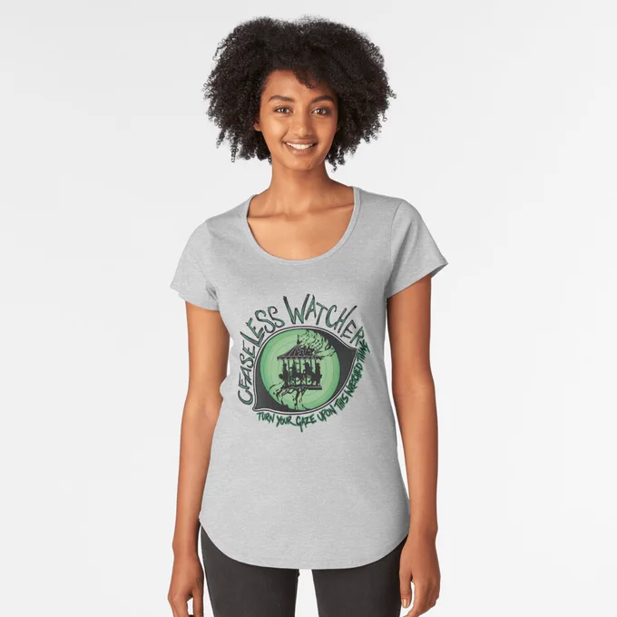 A mock-up of a person wearing a grey t-shirt. The t-shirt features a green and black design of an eye. Within the eye, instead of a pupil is a creepy carousel. Text around the eye reads "Ceaseless Watcher turn your gaze upon this wretched thing".