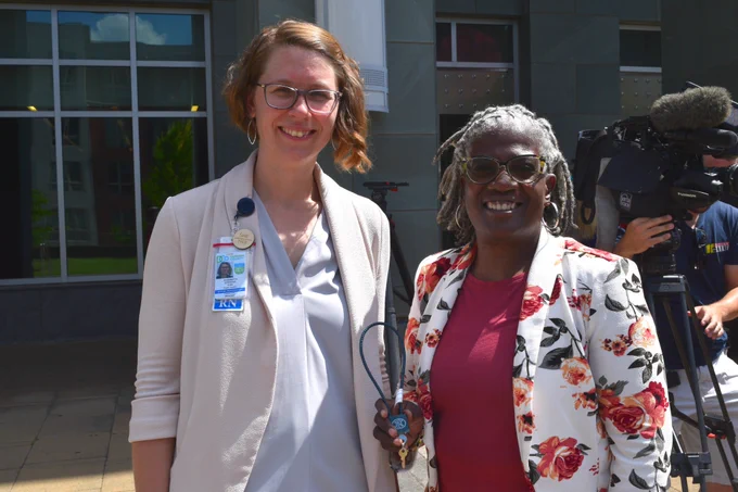 Two women, Liz Stevens, Deputy Public Health Director, and Satana Deberry,  Durham County District Attorney, smiling and holding up a gun lock