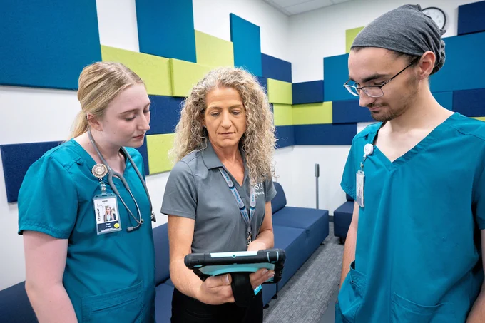 HSC nursing students and a teacher viewing a tablet. 