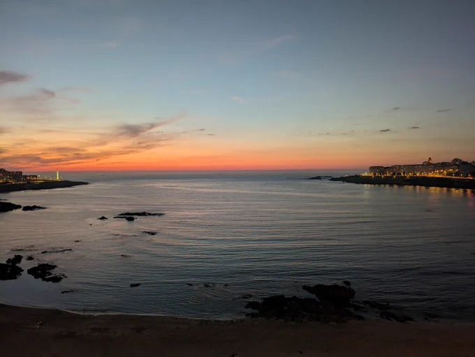 Picture of Riazor beach during sunset, with some red, orange and blue colors in the sky; forecasting good weather for tomorrow.