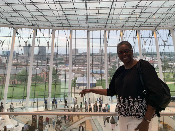 African-American female posing at the Kauffman Center with the background of the city.