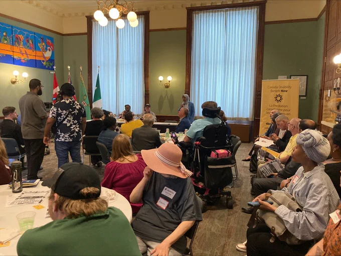 Participants sit at tables and listen to speakers at the Disability Without Poverty's "Better the Benefit" campaign kickoff