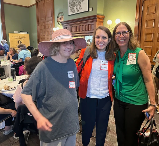 Three smiling TNG Community Services representatives, including Director of Community Programs Serena Nudel (center), gather at the Disability Without Poverty's "Better the Benefit" campaign kickoff