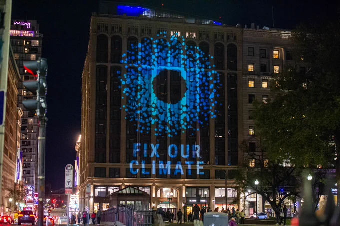 Image of the Little Building at Emerson College with a light installation projected onto it that reads "Fix our Climate."