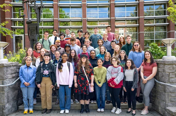 Approximately 50 students  stand in six rows for an outdoor photo on the WSU Pullman campus.