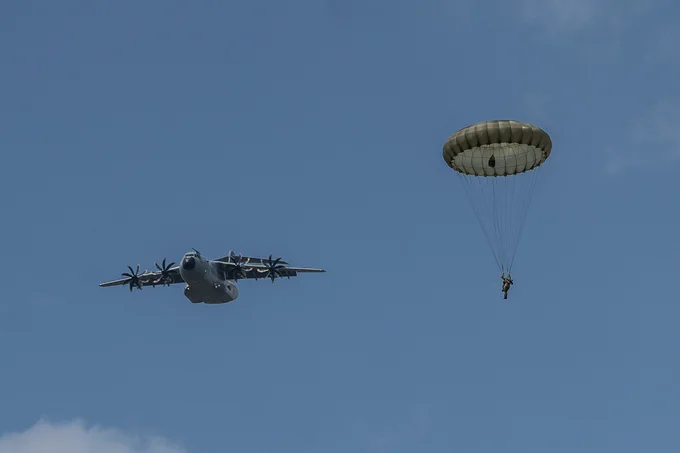 Paratrooper to the right, A400M flying to the left.