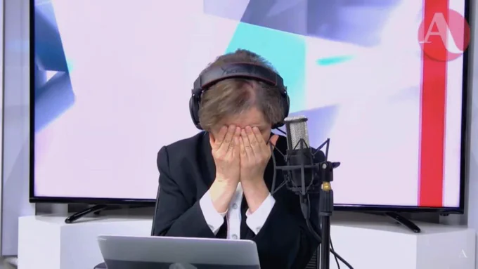 Carmen Aristegui presses her face into her hands while broadcasting from a makeshift newsroom