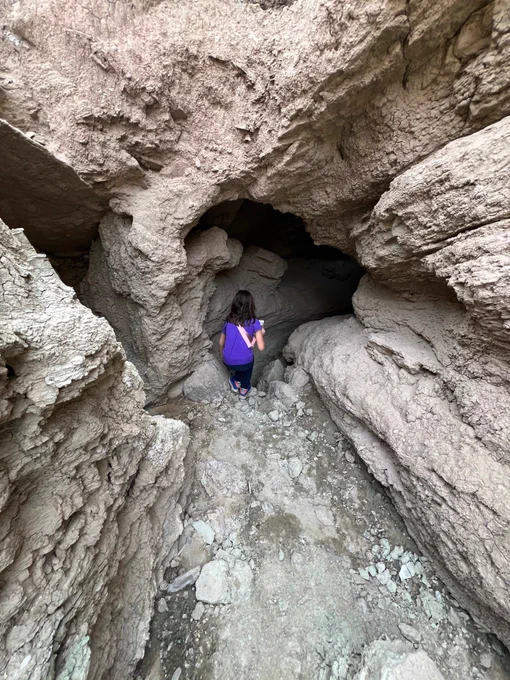 A child peers into a cave.