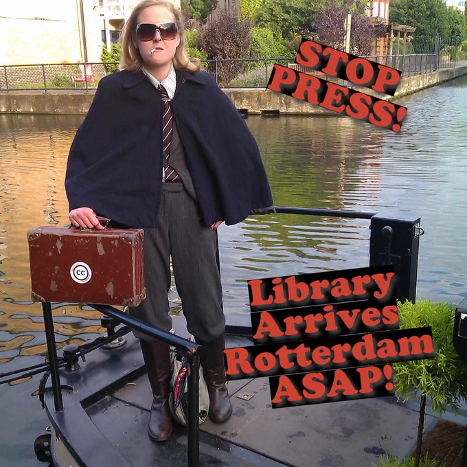 Image of The Itinerant Poetry Librarian on a boat on the water, with text on image announcing "Library Arrives Rotterdam ASAP!".