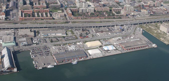 A mostly empty parking lot and some warehouses, seen from the air. 