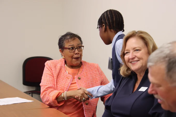 Sharon Porter Robinson from the KBE shaking hands with a student sitting next to Holly Bloodworth