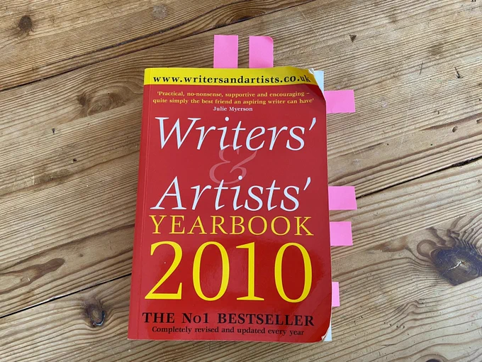 An old battered copy of Writers’ & Artists’ Yearbook 2010 (red cover). Wood table backdrop.