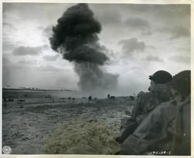 A black and white photograph of Allied ships descending upon Normandy.