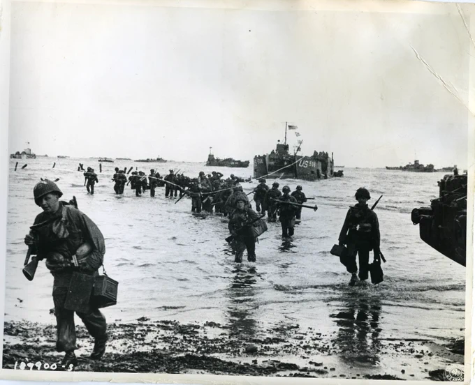 A black and white photograph of Allied ships descending upon Normandy.