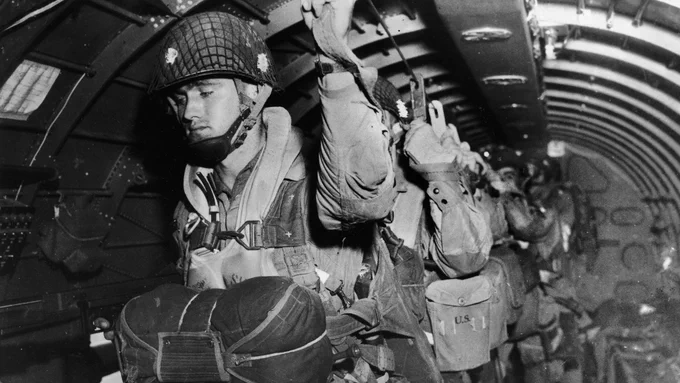 U.S. paratroopers from the 82nd and 101st Airborne Divisions fix their static lines in preparation for a jump before dawn over Normandy on D-Day June 6, 1944. U.S. Army photo.