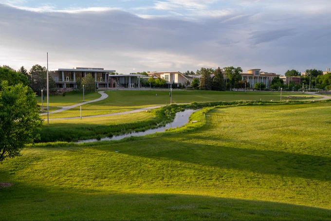 A green, grassy view of Colorado State University's beautiful campus under a light, cloudy sky. 