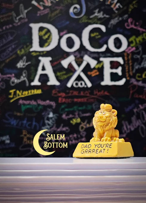 Wallace Berrie "Dad You're Grrreat" Lion pale yellow statuette for sale by Salem Bottom situated in front of DoCo Axe's Wall of Fame with bright, colorful signatures and company logo