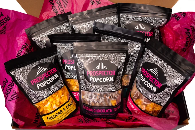 Eight assorted flavors of gourmet popcorn sit in a gift box