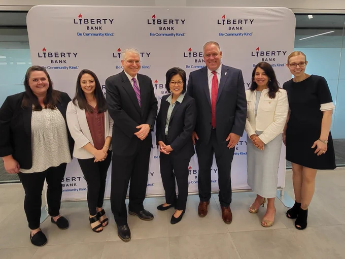 Members of the U.S. Attorney's Office, FBI, and Liberty Bank pose for a photo in front of a backdrop.