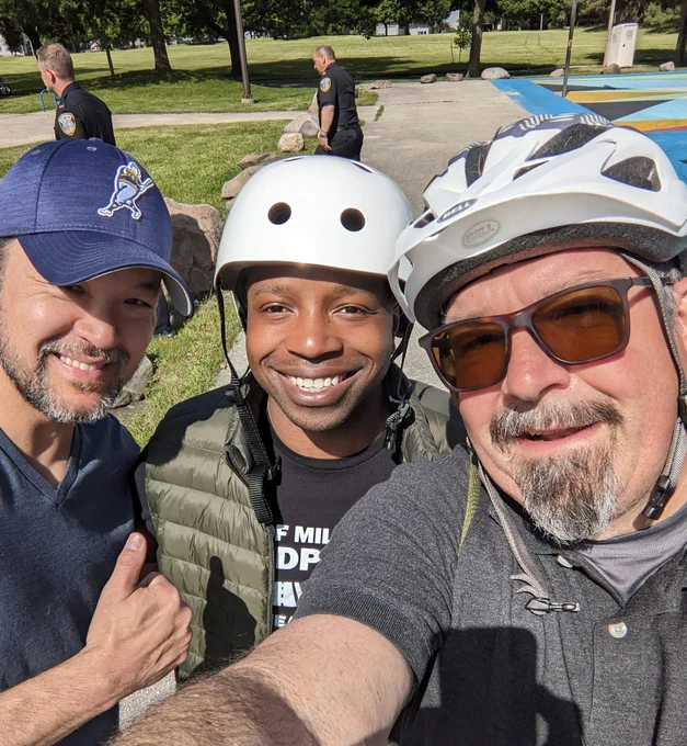 Three men, two have bike helmets on