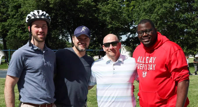 Four men, one has a bike helmet on