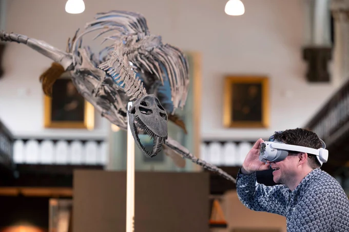 a person wearing a VR headset is looking at a mounted skeleton in a museum gallery