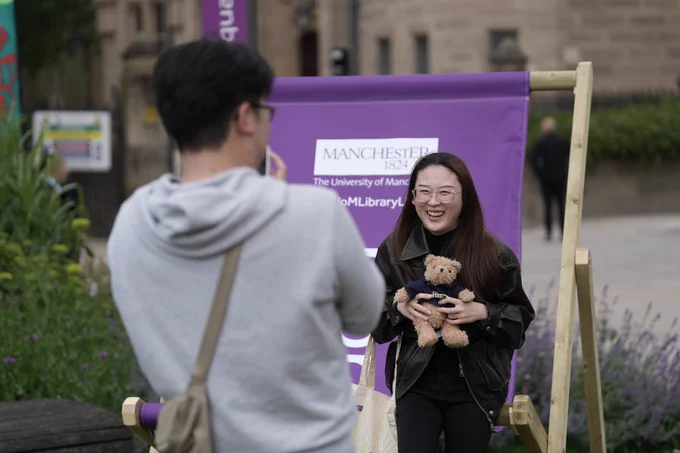 A student laughing holding a teddy bear