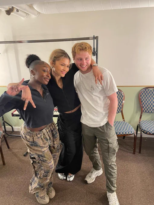 A photo showing three individuals in a dressing room posing for a photo