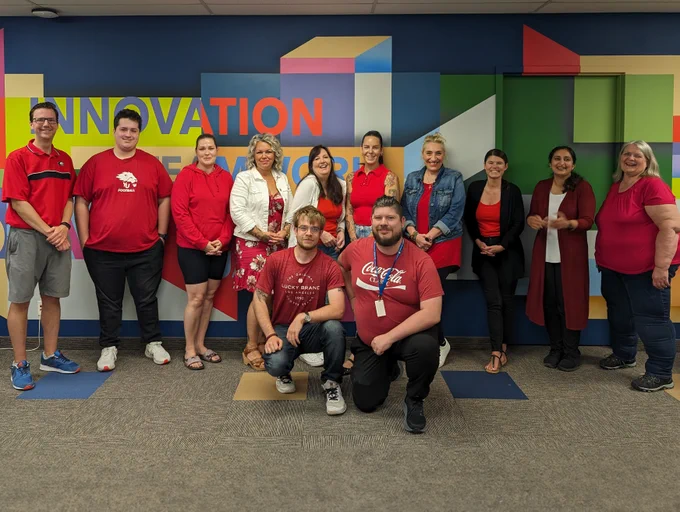 Staebler employees all wearing red shirts pose for a team photo in front of a colourful wall