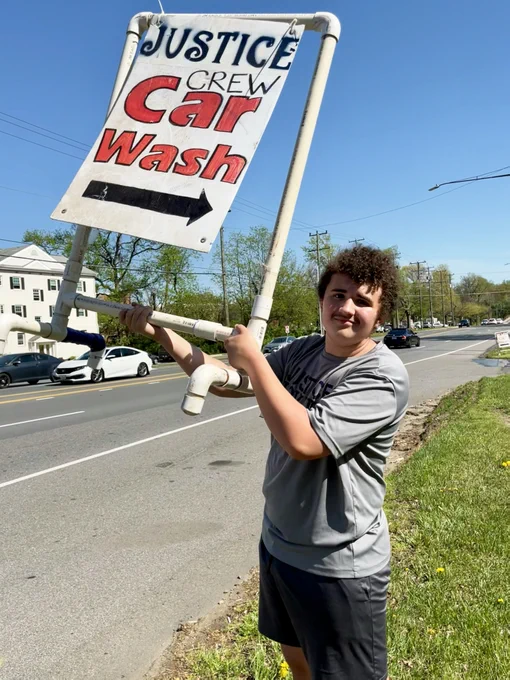 Justice Rower holding sign for June 9 car wash
