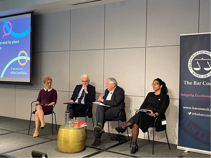 A panel of speakers sitting on a stage with Bar Conference 2024 branding. The speakers are: Lisa Webley, David O'Mahony, Lord Clement-Jones and Shobana Iyer. Lord Clement-Jones is speaking.