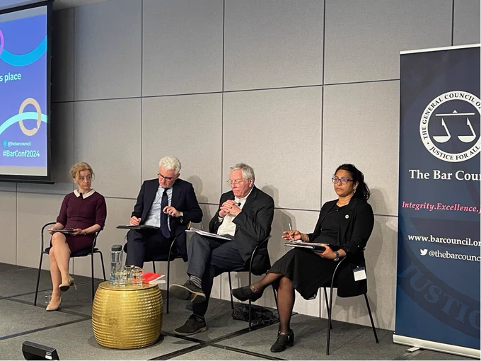 A panel of speakers sitting on a stage with Bar Conference 2024 branding. The speakers are: Lisa Webley, David O'Mahony, Lord Clement-Jones and Shobana Iyer. Shobana is speaking.