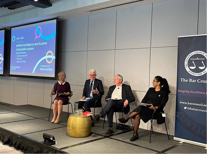 A panel of speakers sitting on a stage with Bar Conference 2024 branding. The speakers are: Lisa Webley, David O'Mahony, Lord Clement-Jones and Shobana Iyer. David is speaking.
