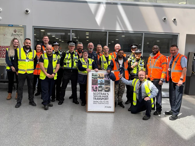 Staff from ScotRail and BTP officers stop for a quick photo at Haymarket station in front of a sign advertising ScotRail's Taylor-Made Transport!
