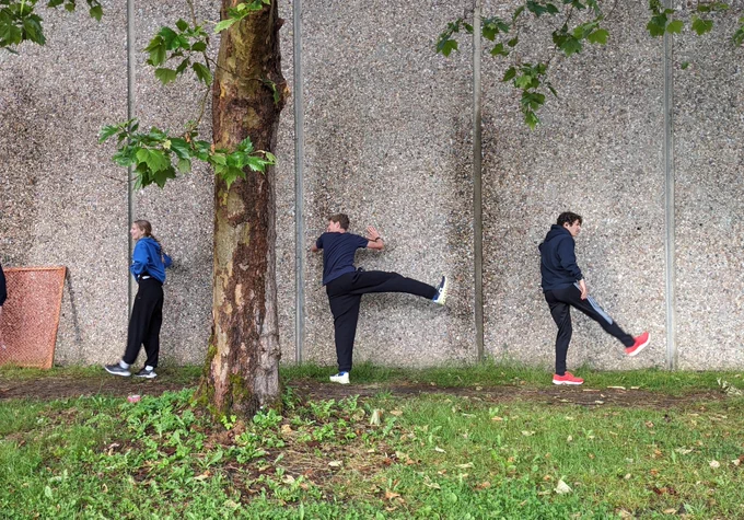 Athletes stretch along side the swimming pool building. 