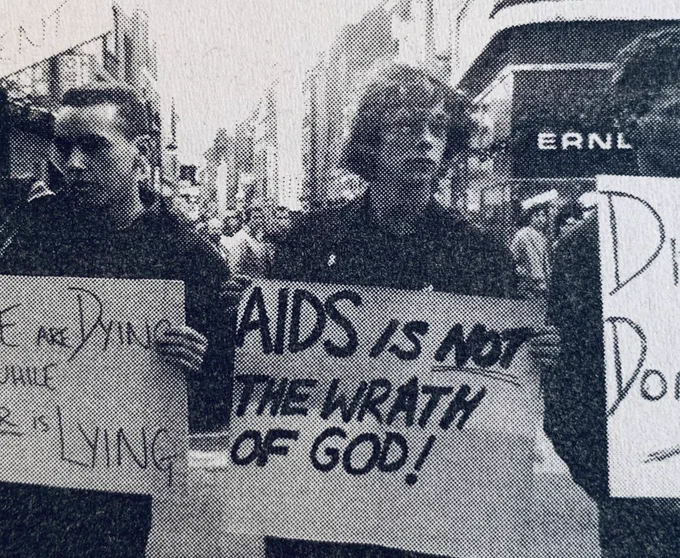 Me on a protest in London in 1987 holding a placard that reads ‘AIDS is NOT the wrath of God!’
The photo is grainy, as it’s taken from a newspaper clipping. 
My hair is awesome.