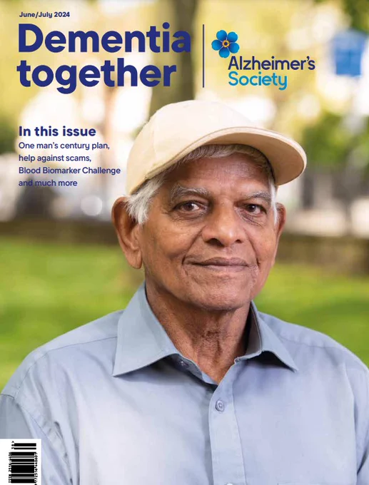 The image is the front page cover of 'Dementia Together' which features a portrait photograph of a man wearing a light blue shirt and a cream coloured baseball cap. He is looking into the camera and smiling. Behind him is grass and buildings, out of focus.