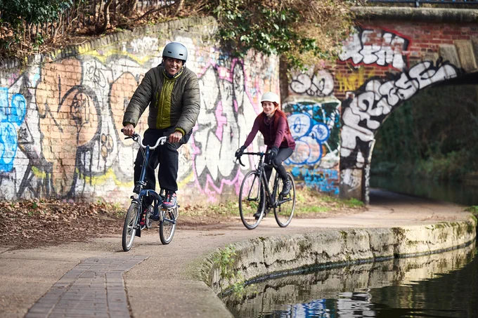 Two Adults Cycling close to a canal.