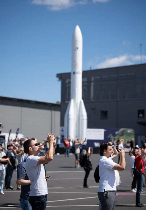Visitors to Berlin Air Show ILA 2024 backdropped by a model of an Ariane 6 rocket.