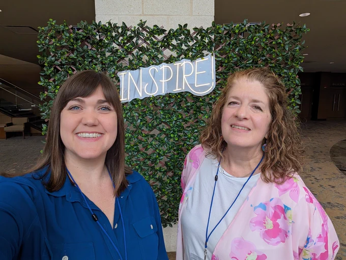 Laura and Kathryn in front of a garden wall with the word INSPIRE