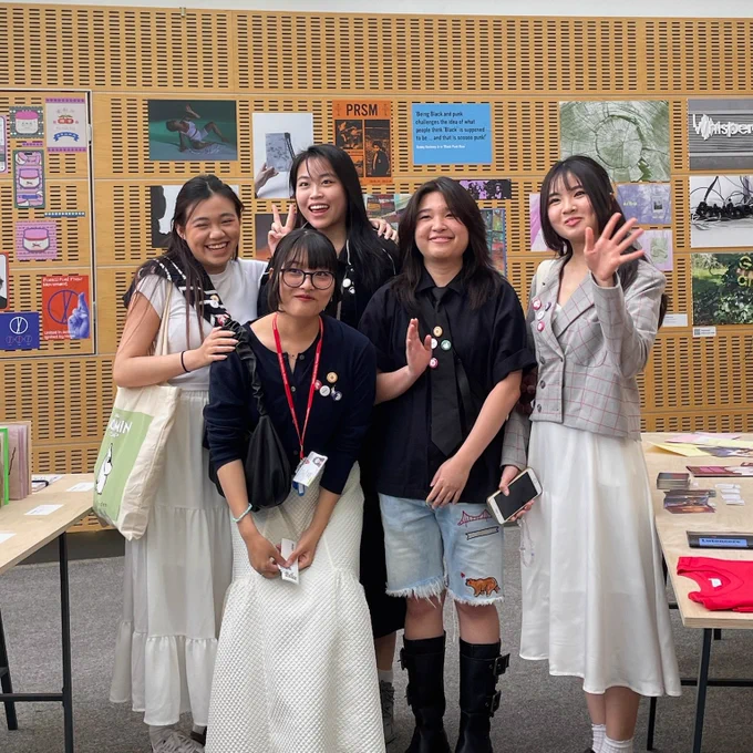 Group of graphic design students smiling in front of their work