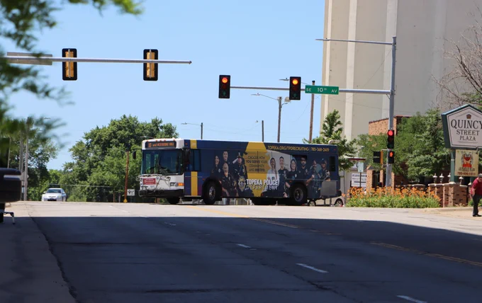 A Topeka Metro bus with a TPD recruitment ad made by Houck Advertising turns north on Quincy St. at 10th St.