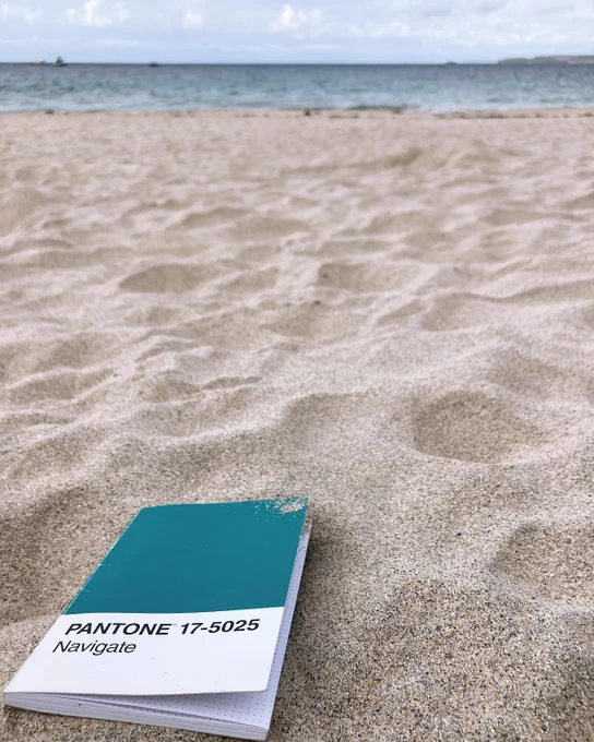Image of a notebook entitled 'Navigate' on a sandy beach with sea in the background.