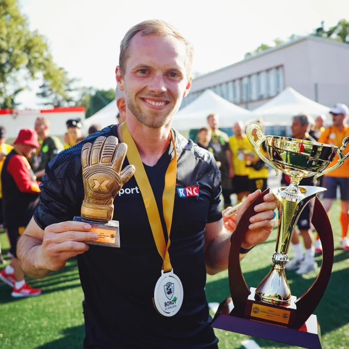 Smiling at the camera holding the best goalkeeper award and the 1st place trophy at the ceremony