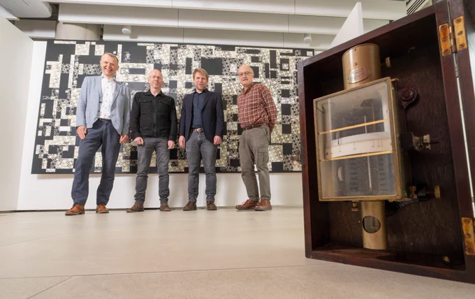 A voltmeter designed by Lord Kelvin Professor stands in the foreground, with (l-r) Dr Stephen Watson of the School of Mathematics & Statistics, artist Gregor Harvie, and Dr Jörg Götte and Professor Stephen Barnett of the University of Glasgow’s School of Physics & Astronomy in front of Gregor Harvie’s Kelvin-inspired artworks on display at the University of Glasgow’s Mazumdar-Shaw Advanced Research Centre (ARC)