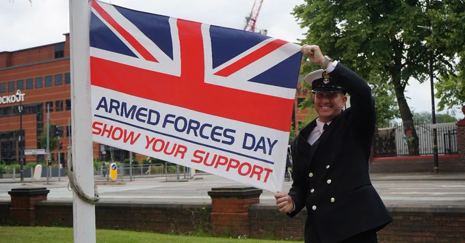 Stuart Hurlston, Detachment Commander of the Trafford Royal Marine Cadets, in military uniform as he holds the Armed Forces Day flag up outside Trafford Town Hall
