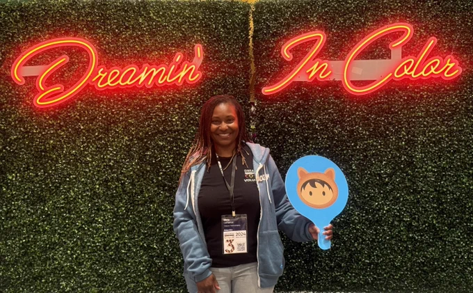 Conference attendee infront of Dreamin In Color sign with Salesforce astro 