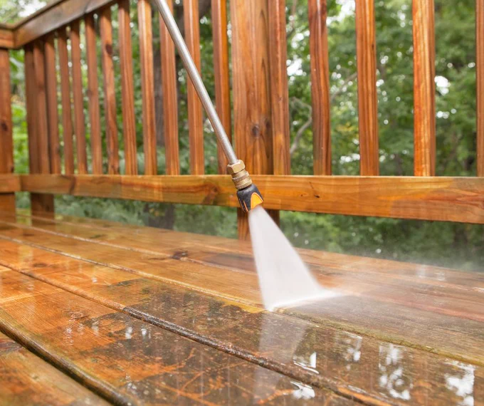 Powerwasher spraying a wood deck
