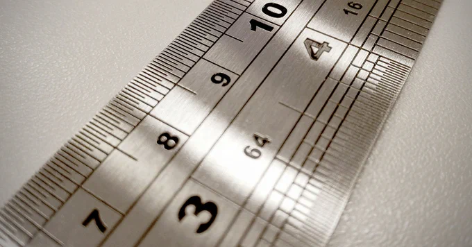 Close up image of a silver ruler on a white background.