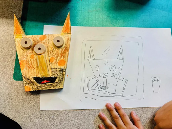 Child's pencil drawing and matching sculpture of a cat-like face.